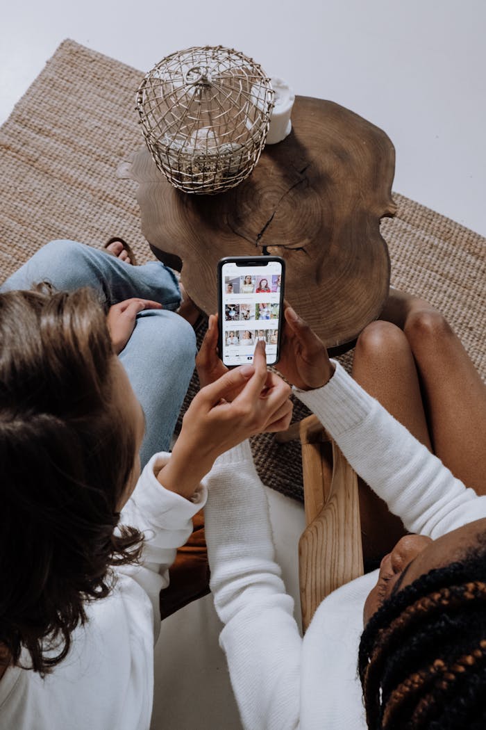 contact-header Two people looking at social media on a smartphone at a wooden table.