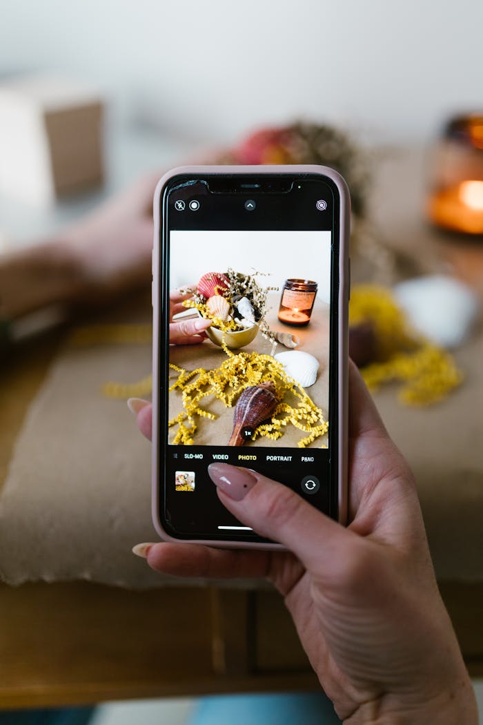 Close-up of hands photographing a colorful still life setup with a smartphone.